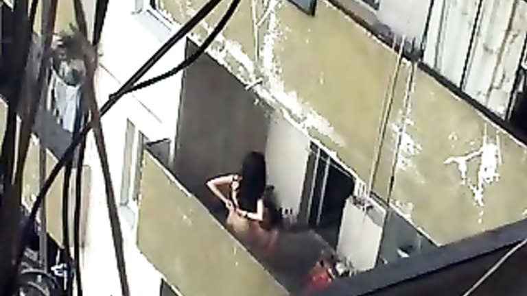 Girl sits on his balls out on the balcony
