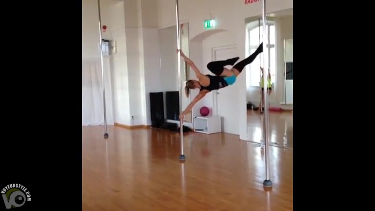 Stunningly fit girl swings around the pole