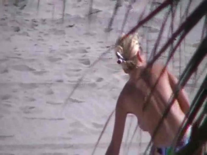 Spying on one busty blonde babe taking a sunbath on beach topless