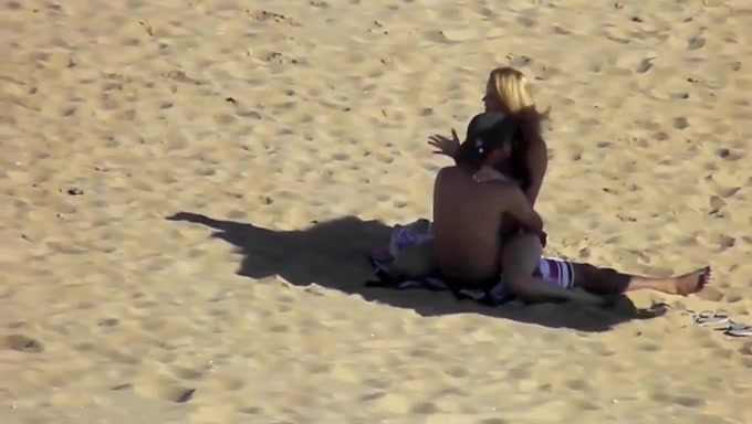 Hidden cam scene with a couple banging in the cowgirl pose on a beach